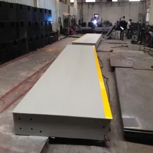 Workers installing vehicle scales weighbridge on‑site for industrial truck weighing project